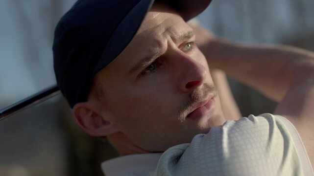 Tight closeup of a golfer&rsquo;s face in Sion, Switzerland showing intense focus after a shot. Authentic sports emotion, concentration, and calm alpine golf course atmosphere.