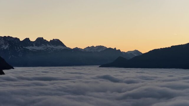 Alpine mountain silhouettes rising above dense cloud inversion at dawn near Walensee, Switzerland