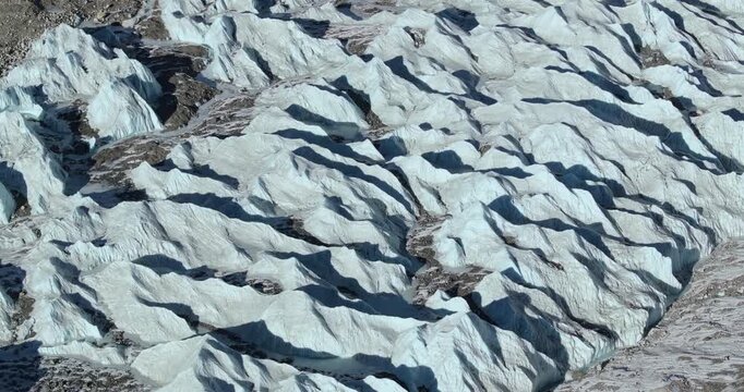 Aerial view of Khumbu Glacier with towering ice formations and glacial meltwater streams beneath the rugged Himalayan peaks in the Everest region of Nepal.