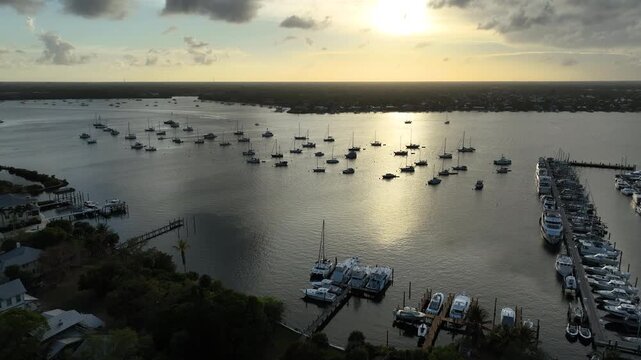A high-altitude aerial shot reveals the peaceful marina landscape of Stuart&rsquo;s Sunset Bay Marina glowing under warm golden hour light.