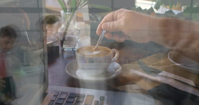 Right hand entering frame and lowering teaspoon, stirring white cup near laptop for business work