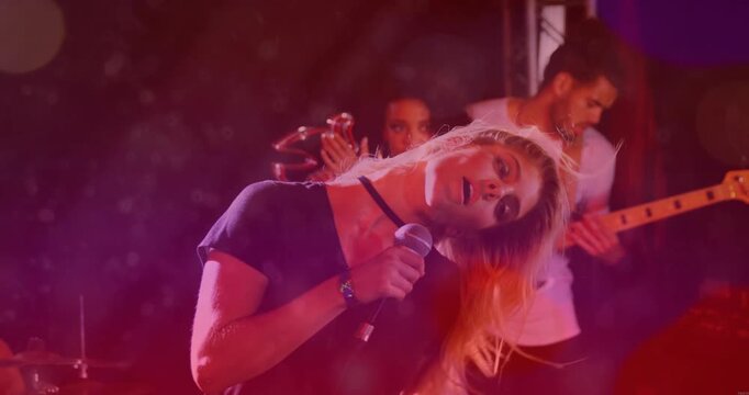 Camera rising revealing lead singer singing into mic head whipping hair settling band playing music