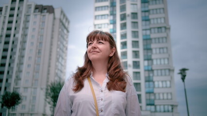 happy woman stands against the background of houses looks at the sky and enjoys the dawn, the beginning of a new positive day, have fun and enjoy © vla