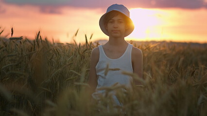 Fototapeta premium Boy Standing in Wheat Field at Sunset Wearing White Tank Top, have fun and enjoy