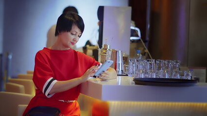 Woman in Red Sweater Using Smartphone at Bar Counter, have fun and enjoy
