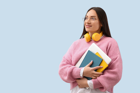 Beautiful young female programmer with laptop and notebook on blue background