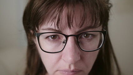 Fototapeta premium serious brunette woman with glasses attentively looks at the camera close-up, observes, moving camera, have fun and enjoy