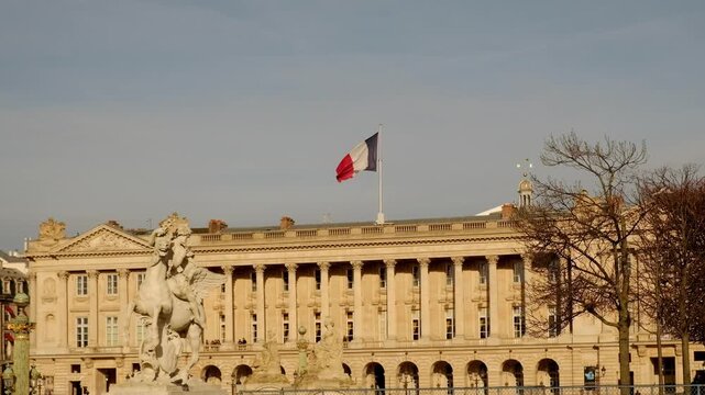 Elegant view of the Hotel de la Marine on Place de la Concorde in Paris, with French flag flying above its neoclassical facade under a clear blue sky.