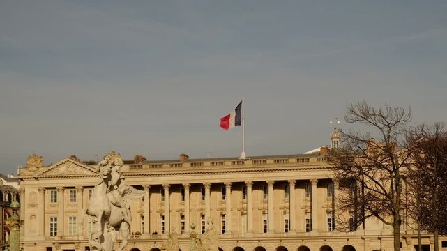 Elegant view of the Hotel de la Marine on Place de la Concorde in Paris, with French flag flying above its neoclassical facade under a clear blue sky.