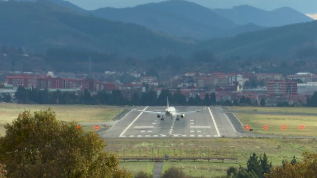 Airplanes landing at Bilbao Airport during strong southern winds. Aircraft move noticeably while touching down on the runway, illustrating challenging weather conditions and aviation operations.