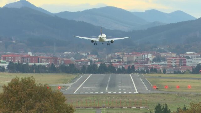 Airplanes landing at Bilbao Airport during strong southern winds. Aircraft move noticeably while touching down on the runway, illustrating challenging weather conditions and aviation operations.