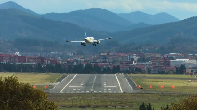 Airplanes landing at Bilbao Airport during strong southern winds. Aircraft move noticeably while touching down on the runway, illustrating challenging weather conditions and aviation operations.