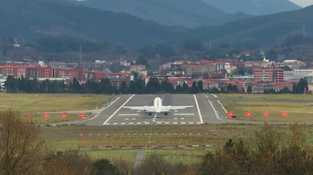 Airplanes landing at Bilbao Airport during strong southern winds. Aircraft move noticeably while touching down on the runway, illustrating challenging weather conditions and aviation operations.