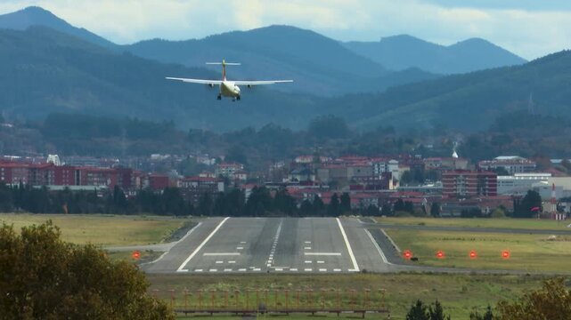 Airplanes landing at Bilbao Airport during strong southern winds. Aircraft move noticeably while touching down on the runway, illustrating challenging weather conditions and aviation operations.