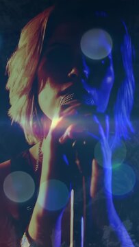 Vertical video: Singer lifting arm, grabbing mic, singing for music, camera widening, bokeh pulsing