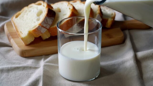 Pouring Milk into Glass with Sliced Bread on Wooden BoardBackground video