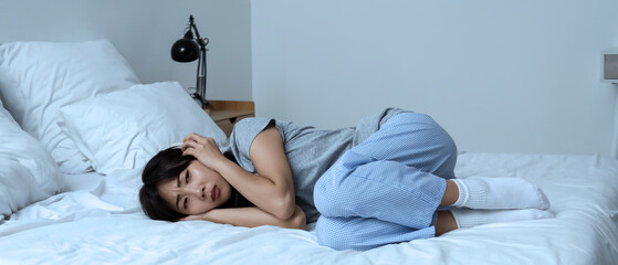 Young Asian woman with suicidal thoughts and headphones lying in bedroom