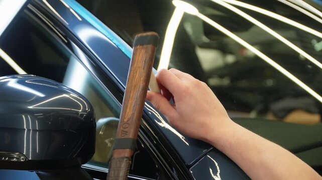 PDR. Process of paintless dent repair on car body. The mechanic at the auto shop with tools to repair dents in car body. Body repair. A specialist repairs a dent on the car body without painting.