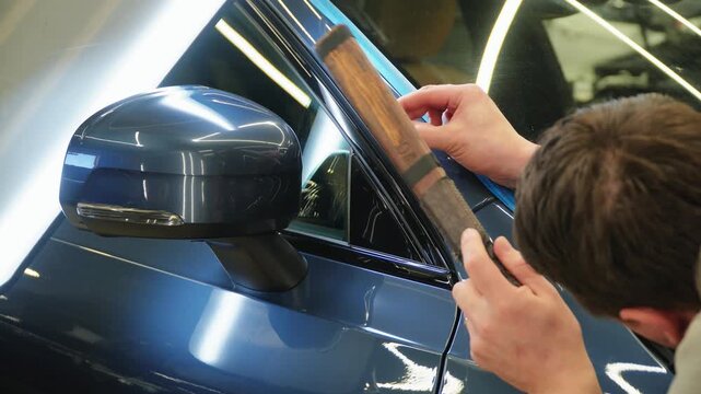 PDR. Process of paintless dent repair on car body. The mechanic at the auto shop with tools to repair dents in car body. Body repair. A specialist repairs a dent on the car body without painting.
