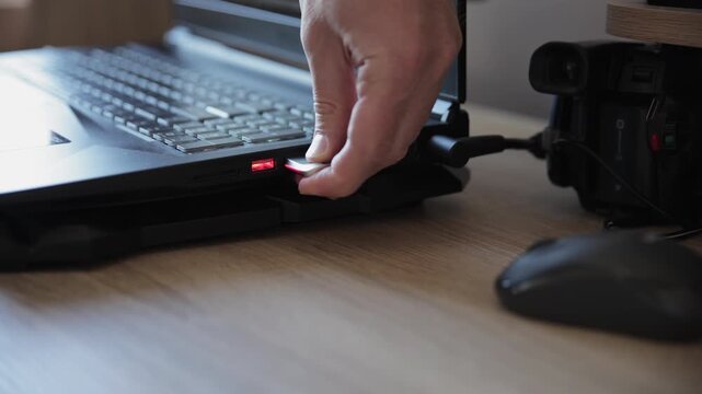 Person Plugging Luminous USB Flash Drive into Laptop Port