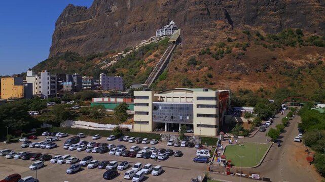 Aerial tilt up shot of Saptashrungi Devi Temple, Vani Nashik, Half Shakti Peetha hilltop shrine, parking area, sky and mountain landscape view on a sunny day, 4K