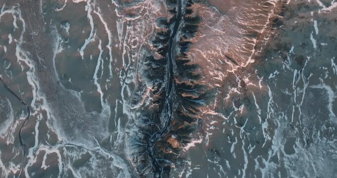Stunning drone footage captures winding rivers flowing through colorful Icelandic landscape with orange brown sediment patterns and geological formations creating natural abstract art