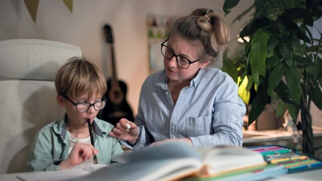A mother and her son are doing homework together, she is correcting his mistakes