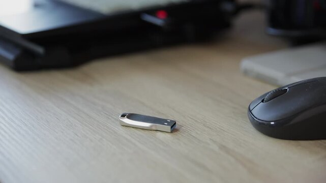 Close-up of a Man's Hand Placing a Metallic USB Flash Drive on a Wooden Desk
