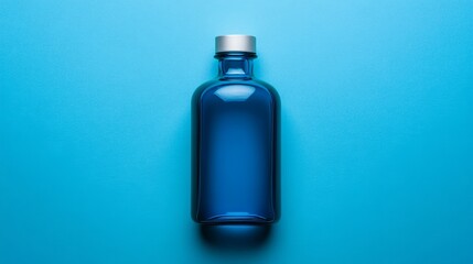 Fototapeta premium A sleek blue glass bottle with a silver cap lies centrally on a vibrant blue background. Minimalistic design