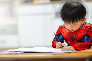 Naklejka premium Toddler Drawing with Pencil at Table at Home