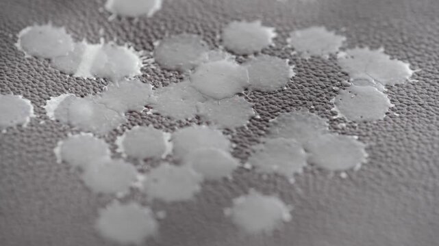 A candle dripping wax leather furniture, creating spots and patterns gray background at a cozy location. Concept of everyday life problem and home cleaning