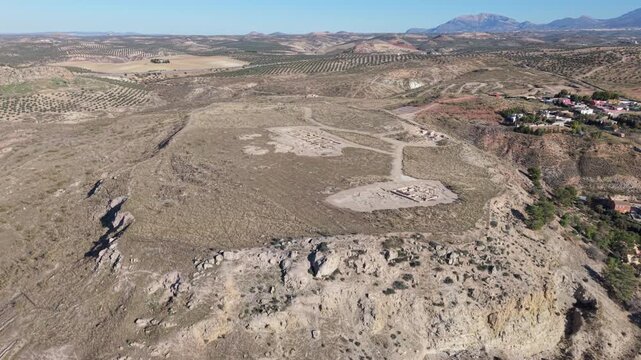 A smooth aerial drone shot flying backwards to reveal the full extent of the Oppidum &Iacute;bero de Puente Tablas, an ancient Iberian archaeological site located atop a hill outside Ja&eacute;n, Andalusia, Spain. 