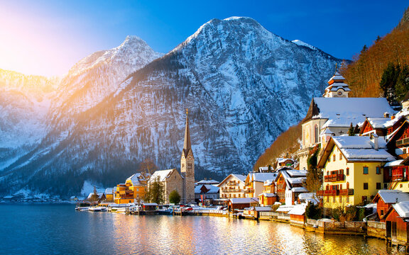 Classic postcard view of famous Hallstatt lakeside town in the Alps with traditional passenger ship on a beautiful cold sunny day with blue sky and clouds in winter, Salzkammergut region, Austria