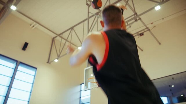 A determined male athlete practices his basketball skills in a modern gymnasium. He dribbles the ball with focus, then shoots and scores, showcasing dedication and training.