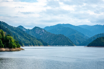 Obraz premium 新潟県奥只見湖の雄大な山並みと水面、夏の終わりの曇り空