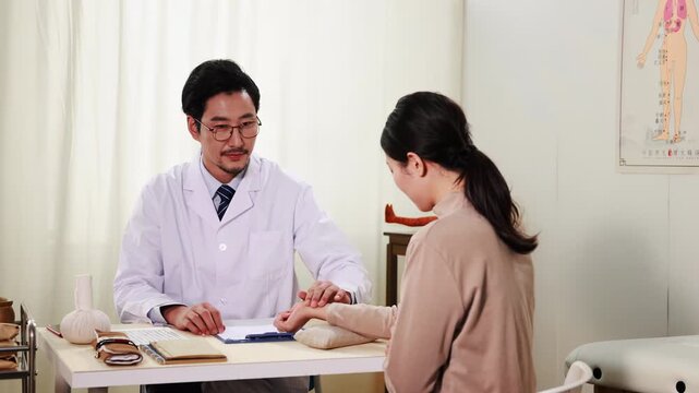 Herbalist oriental medicine doctor checks patient pulse with packages dried herbs nearby, advice instructions drug usage. Emphasizing raditional approach to disease treatment at diagnosis clinic