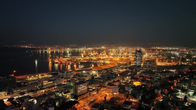Aerial view of Haifa city and port at night with glowing city lights, Israel
