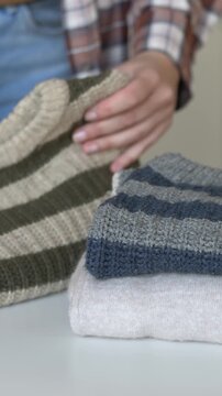 Woman hand handling of old wool sweater being restored for reuse with fabric shaver nearby. Clothing care process fits slow fashion, second life textile and responsible consumption editorial visuals