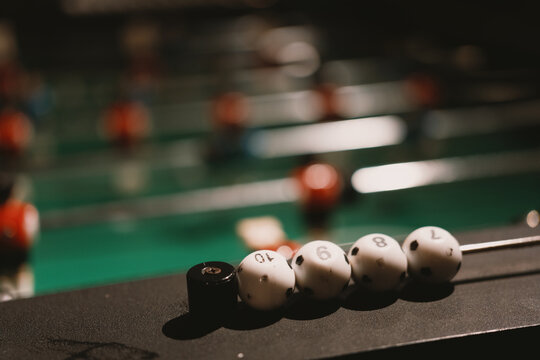 Foosball table with white and black balls in focus, indoor game room setting