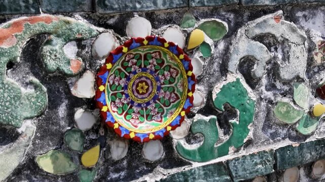 Colorful porcelain rosette set into textured weathered stucco surface Wat Arun