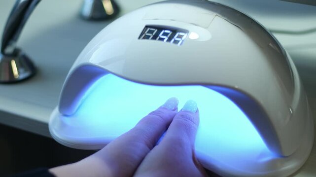 Brief video showing a hand being cured under a UV LED nail lamp for a gel manicure. High quality 4k footage