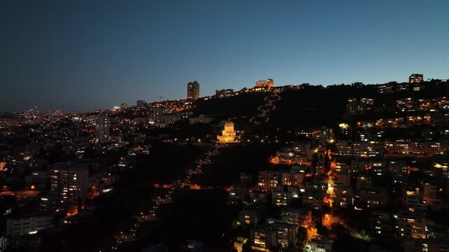 Aerial night view of Haifa with the Baha'i Gardens, German Colony, and the illuminated city port, Israel