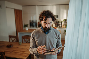 Fototapeta premium Man standing remembering while looking through old book