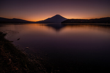 Obraz premium 山中湖に広がる深い夕暮れ色とシルエットの富士山の静景