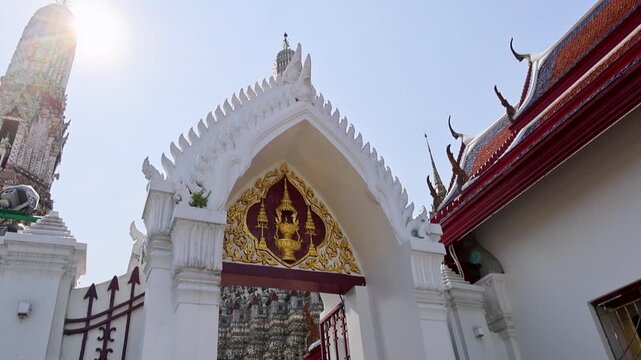 Grand temple entrance adorned with gold and bright sunlight Wat Arun