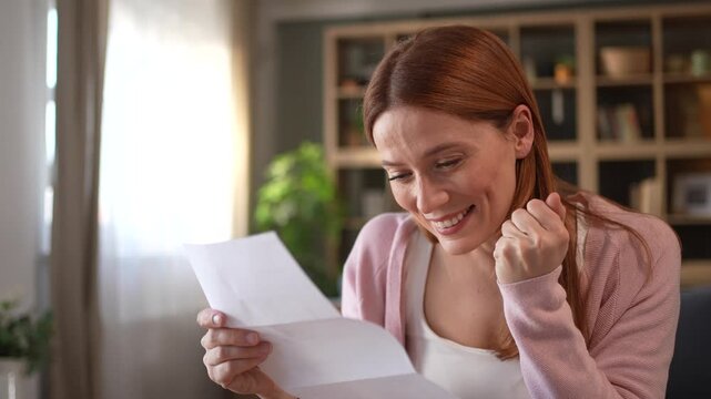 Happy woman reading good news in a letter at home