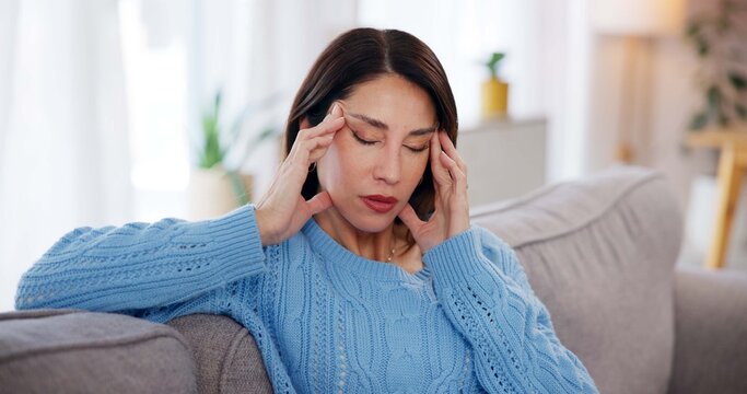 Woman, headache and stress on sofa in home with brain fog, dizzy and muscle tension. Person, migraine and uncomfortable pressure with vertigo, temple massage and overwhelmed with burnout in lounge