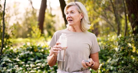 Fototapeta premium Mature woman, hiking and bottle in forest with water, rest and reflection on path with hydration in summer. Person, container and liquid for health, wellness and break with perspective in France