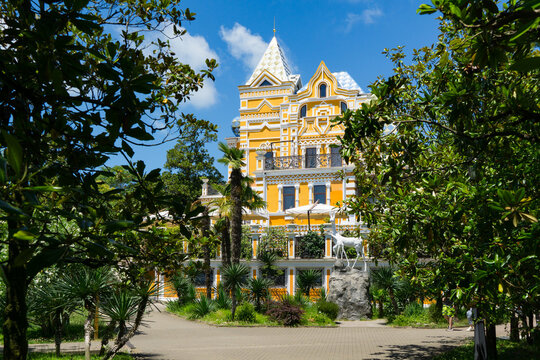 Grand, ornate yellow-and-white Khludov's dacha building. Now boutique hotel Usadba Khludova surrounded by lush greenery and palm trees in Riviera Park. Sochi, Russia - June 30, 2025