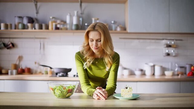 Dieting woman making choice between healthy salad tasty cake at cuisine closeup